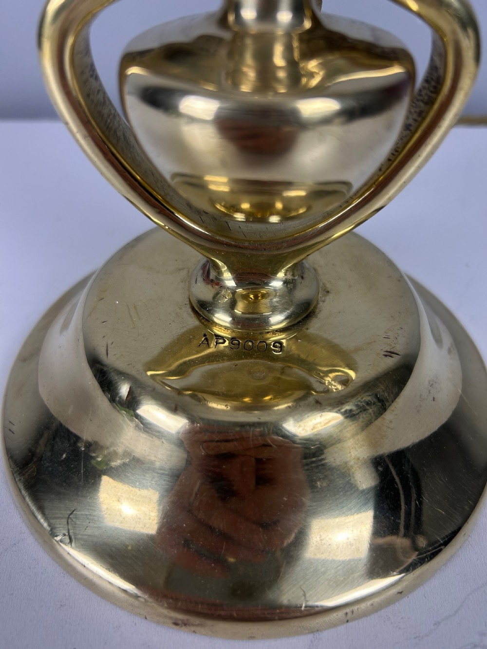 An antique brass gimbal table lamp featuring a circular weighted base, pivoted swinging frame, and exposed bayonet bulb socket. View IX