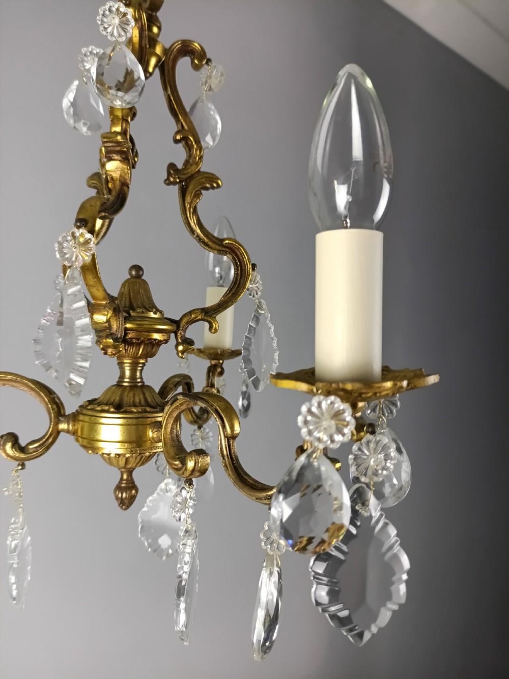A French gilt brass three-arm chandelier featuring curved scrollwork arms, candle-style lamp holders, and dangling faceted crystal droplets. View XI
