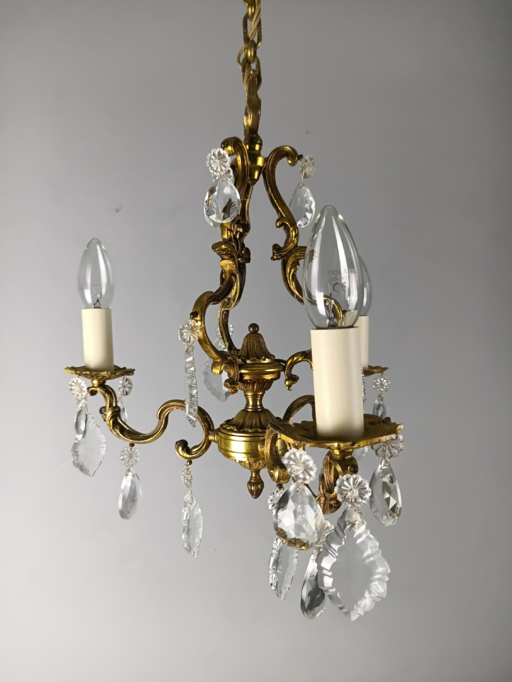 A French gilt brass three-arm chandelier featuring curved scrollwork arms, candle-style lamp holders, and dangling faceted crystal droplets. View XIII
