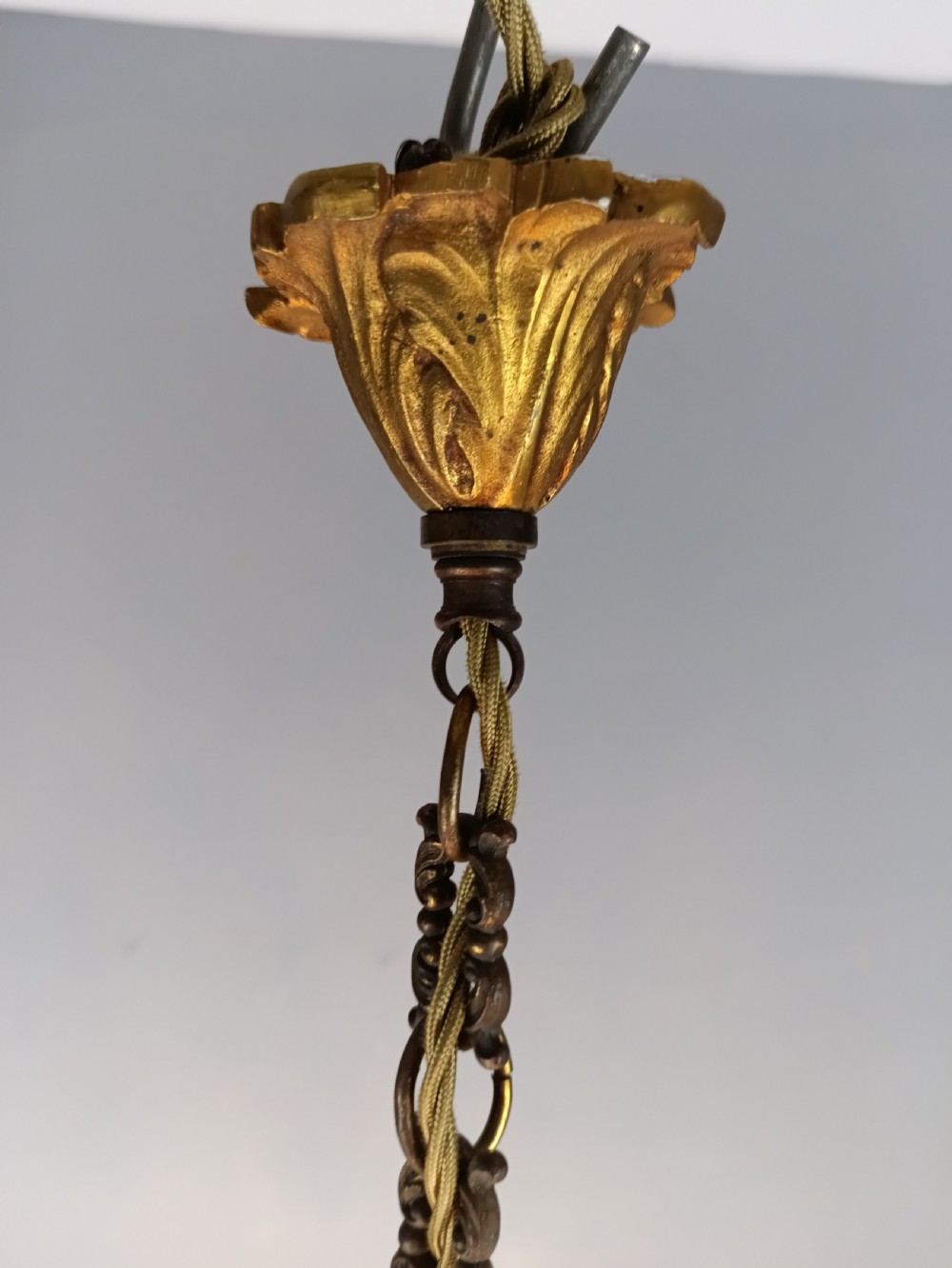 A five-arm French Rococo style chandelier featuring a gilded scrollwork frame adorned with clear faceted crystal drops and white candle sleeves. View III