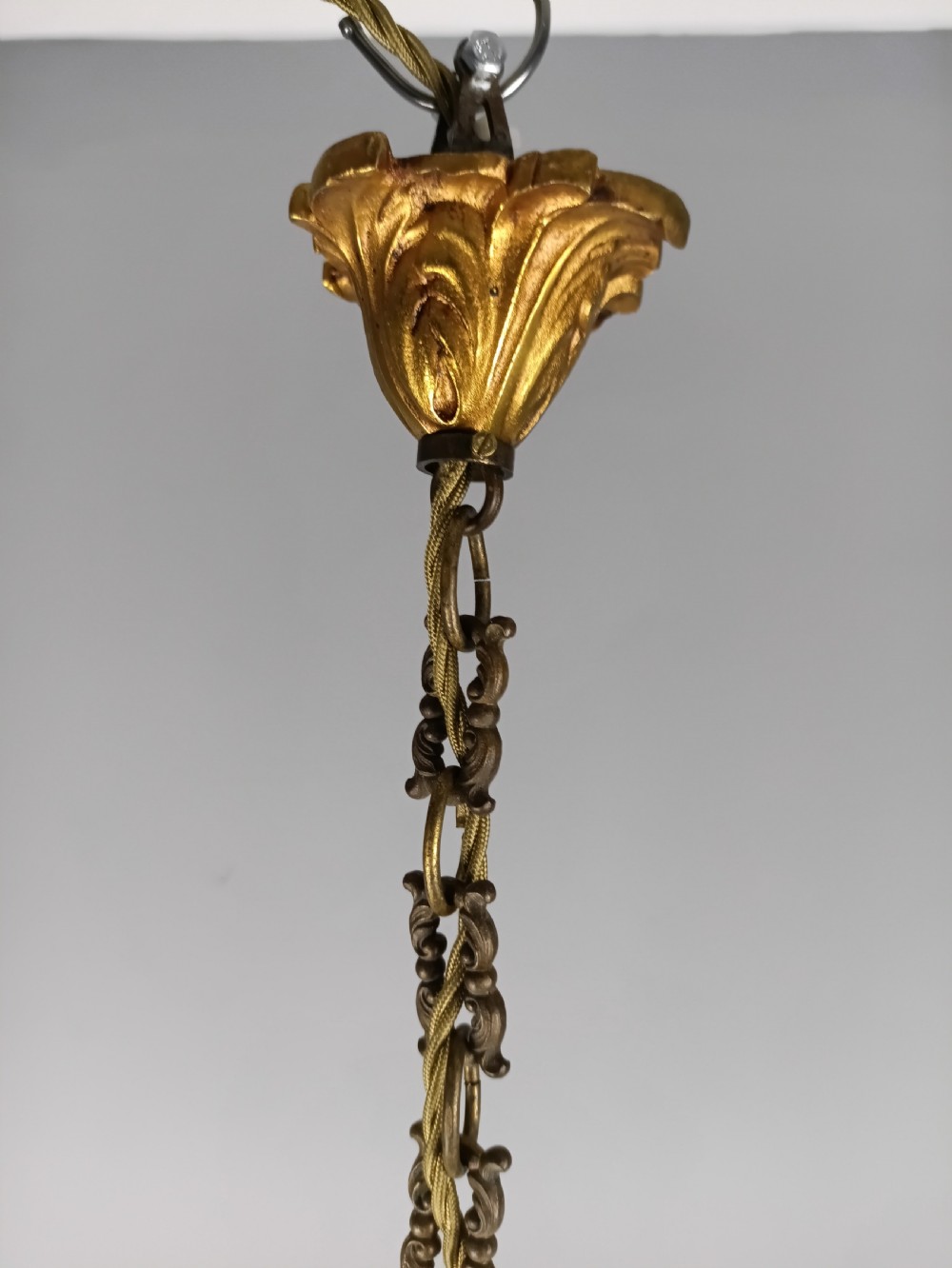 A French gilt brass four-light chandelier featuring curved scroll arms, candle sleeves, and faceted crystal droplets hanging from an ornate central frame. View XII