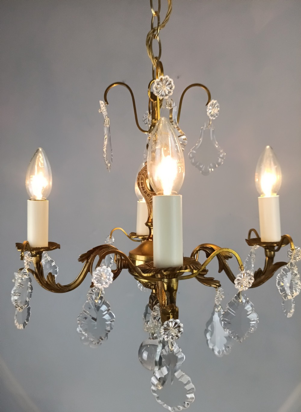 A French gilded brass four-light chandelier adorned with faceted crystal drops and a central crystal sphere finial. View II