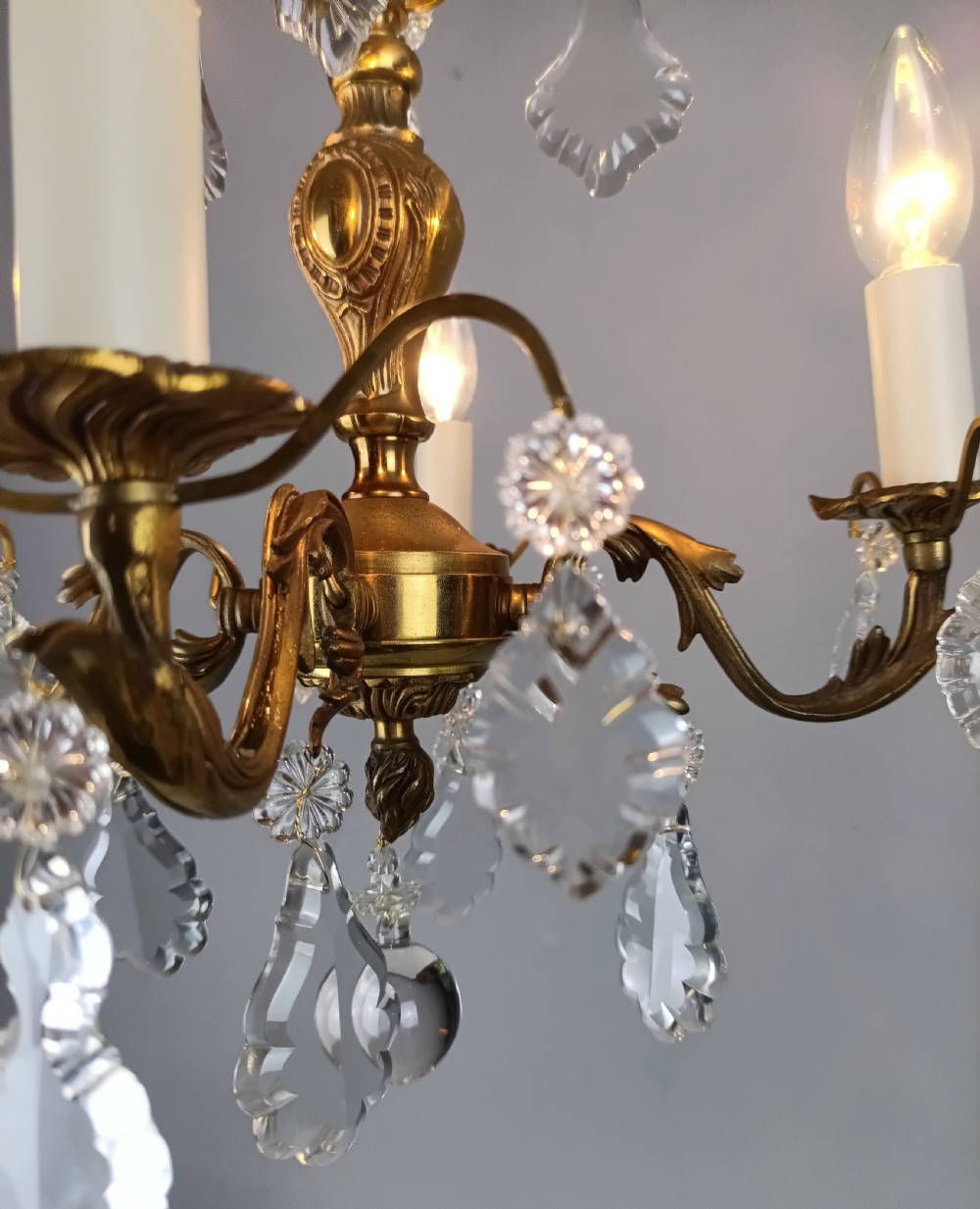 A French gilded brass four-light chandelier adorned with faceted crystal drops and a central crystal sphere finial. View IV