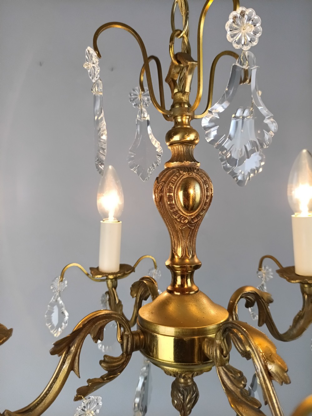 A French gilded brass four-light chandelier adorned with faceted crystal drops and a central crystal sphere finial. View V