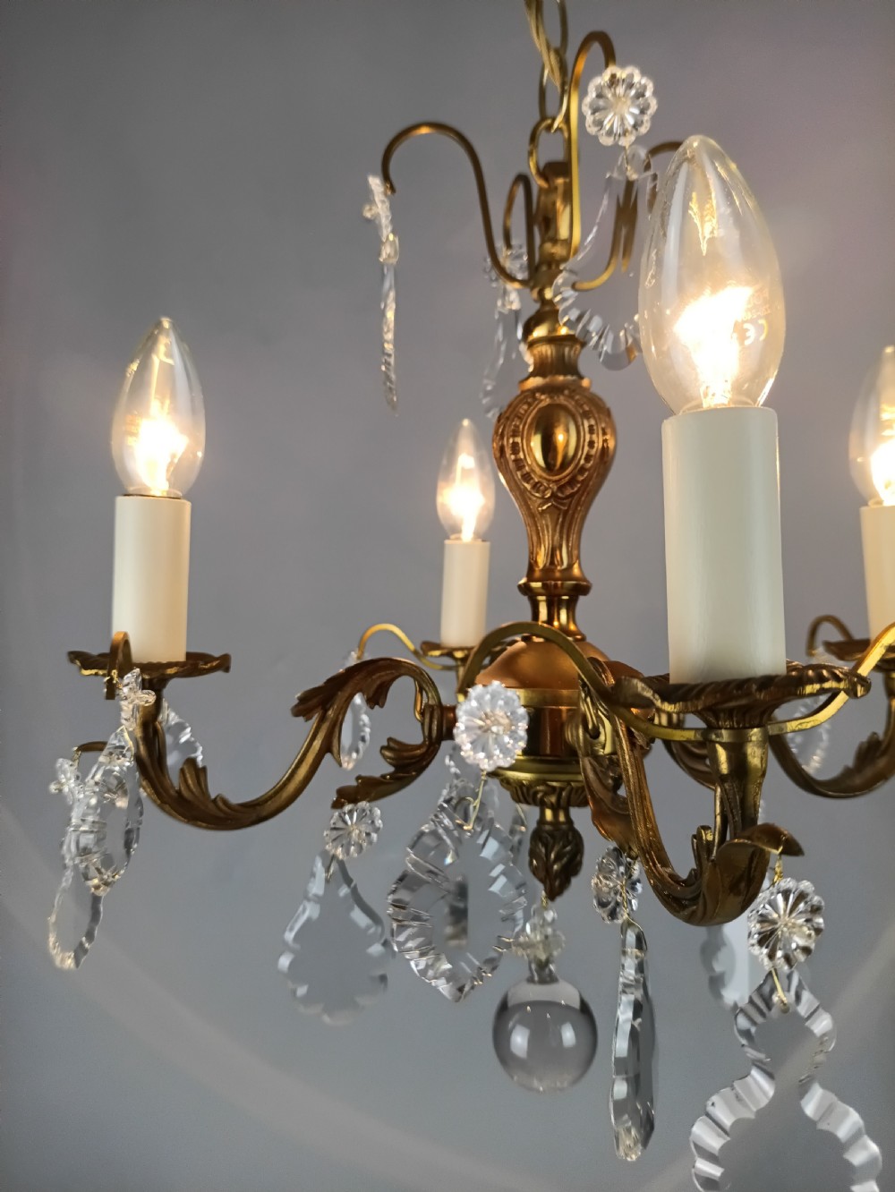 A French gilded brass four-light chandelier adorned with faceted crystal drops and a central crystal sphere finial. View VI