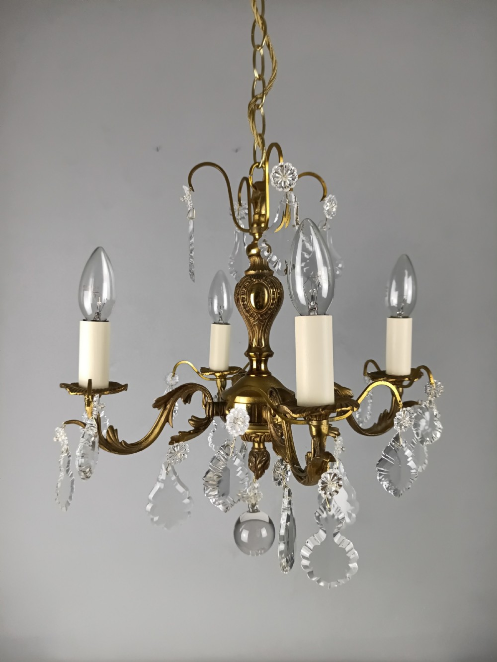 A French gilded brass four-light chandelier adorned with faceted crystal drops and a central crystal sphere finial. View VIII