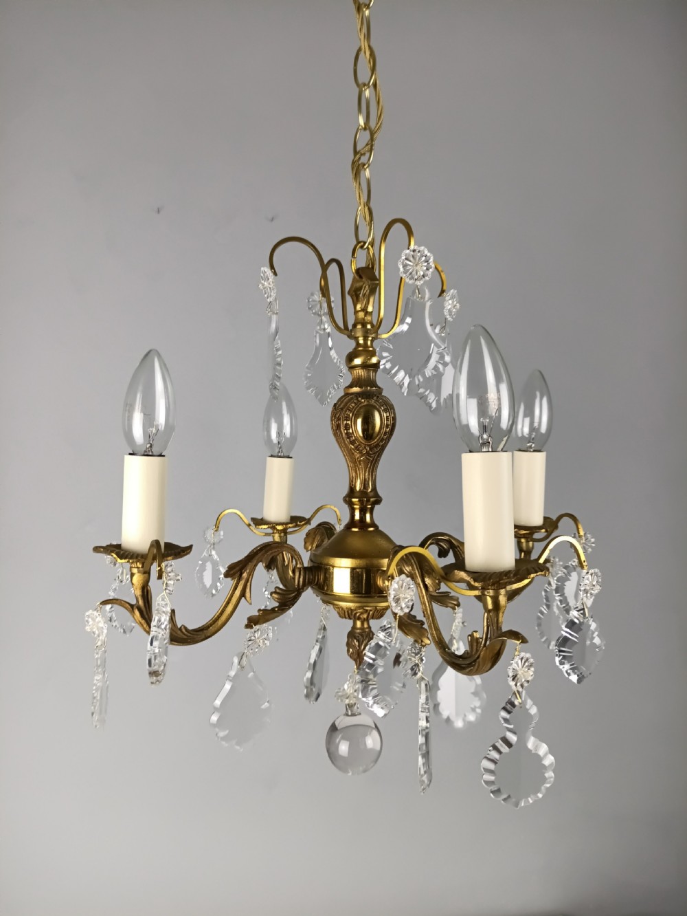 A French gilded brass four-light chandelier adorned with faceted crystal drops and a central crystal sphere finial. View IX