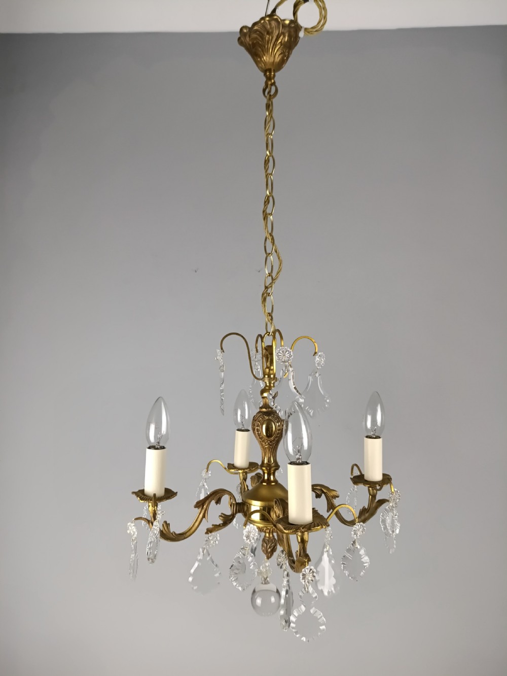 A French gilded brass four-light chandelier adorned with faceted crystal drops and a central crystal sphere finial. View XII