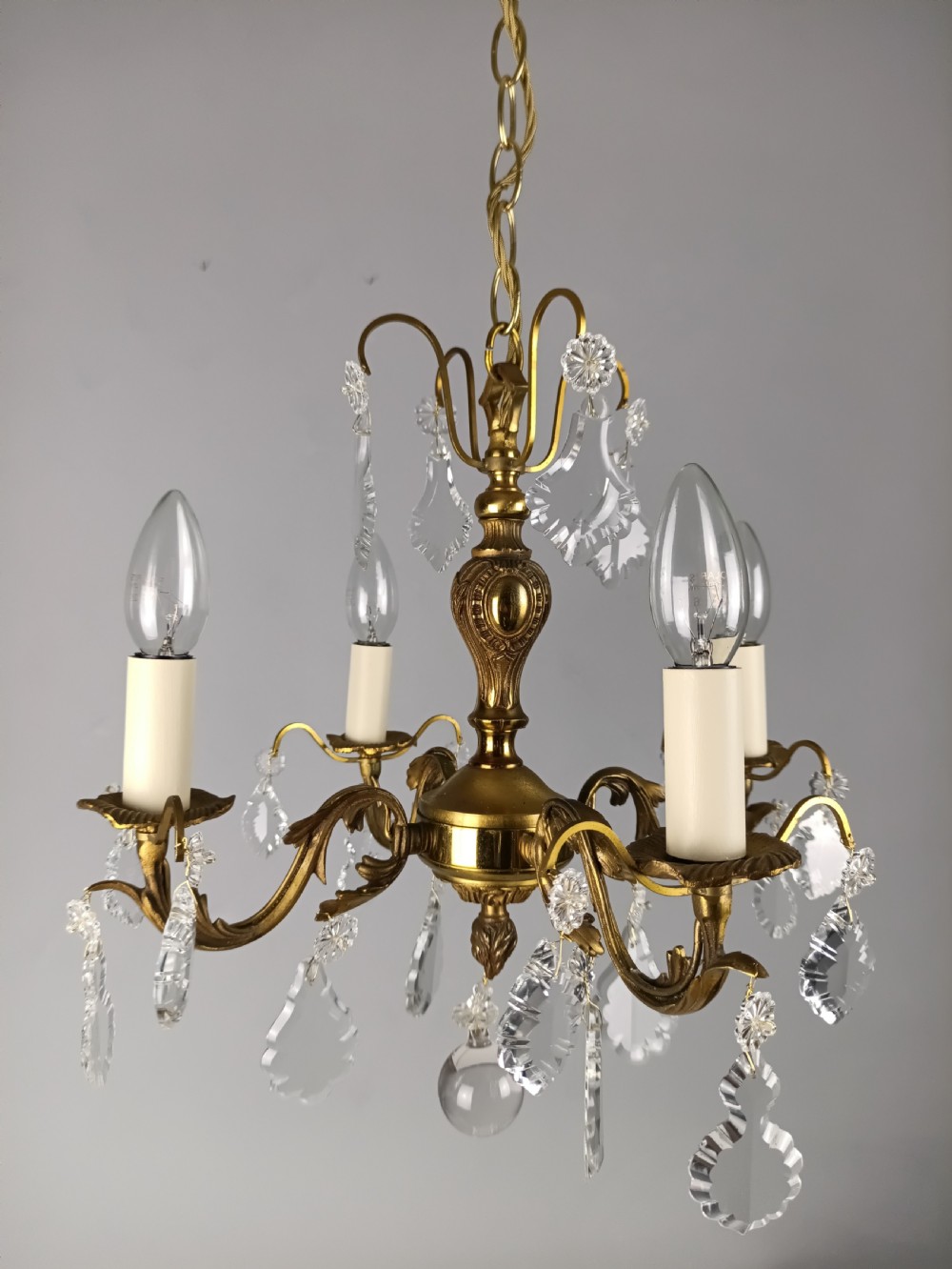 A French gilded brass four-light chandelier adorned with faceted crystal drops and a central crystal sphere finial. View XIII