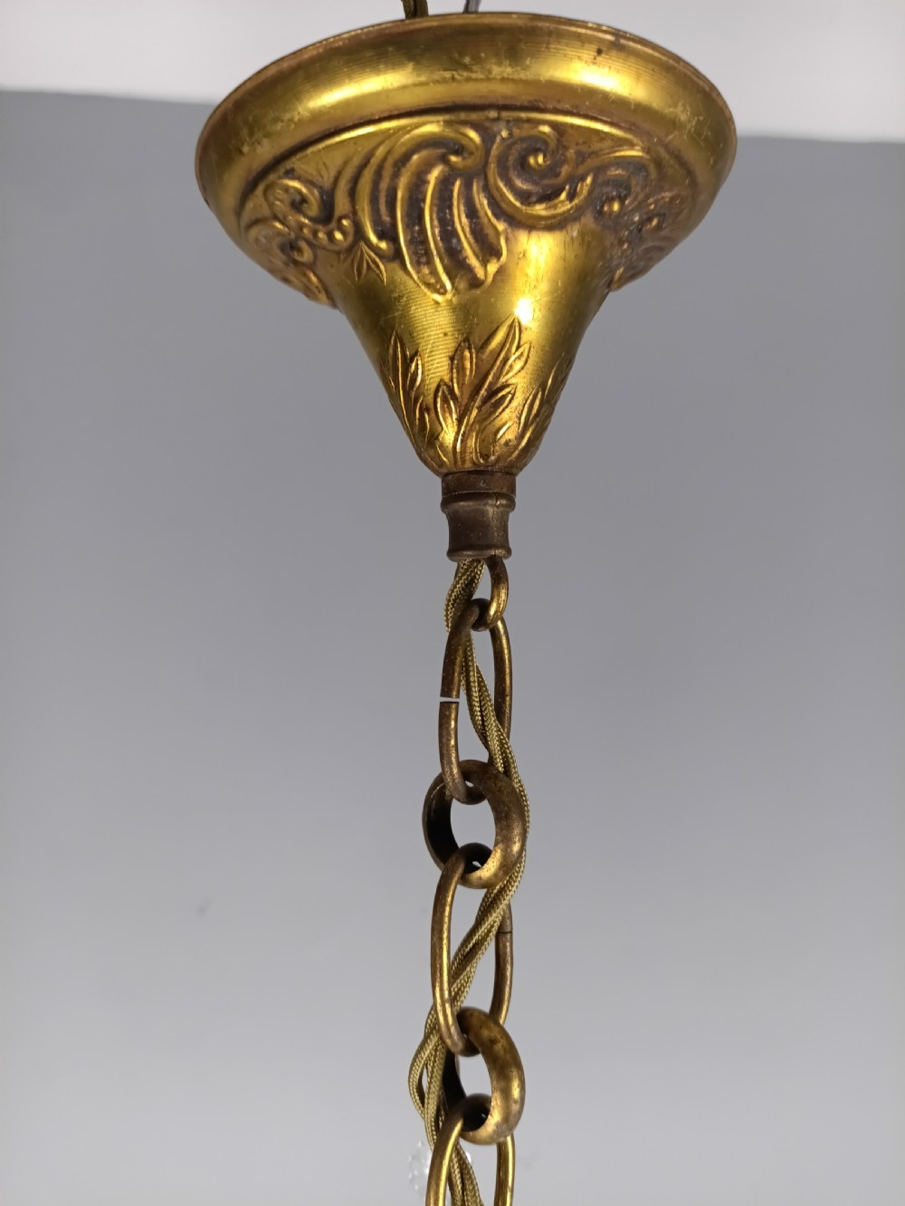 An antique French gilt brass three-light chandelier featuring curved scrolling arms, cream candle-style sleeves, and faceted crystal drops. View VIII