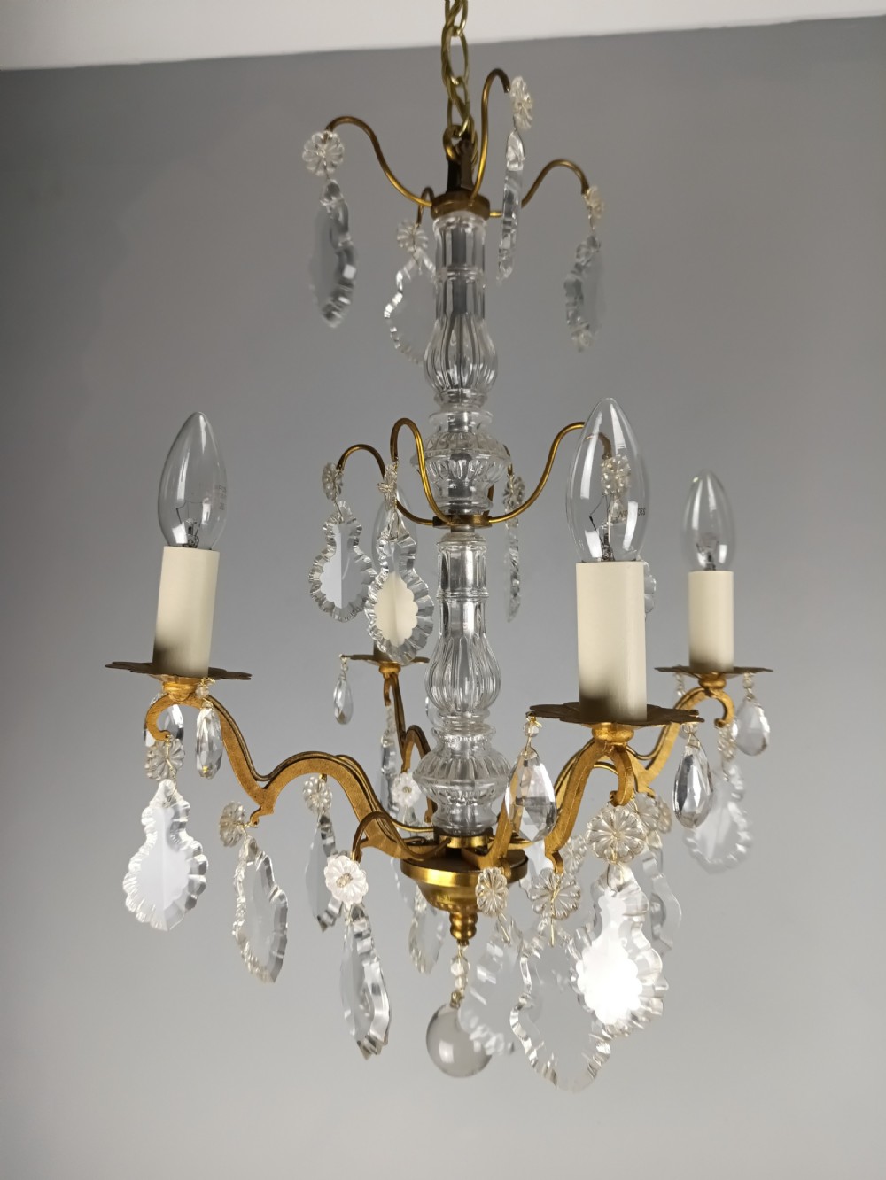 A four-light French gilded brass chandelier featuring a central glass column and hanging cut crystal drops. View III