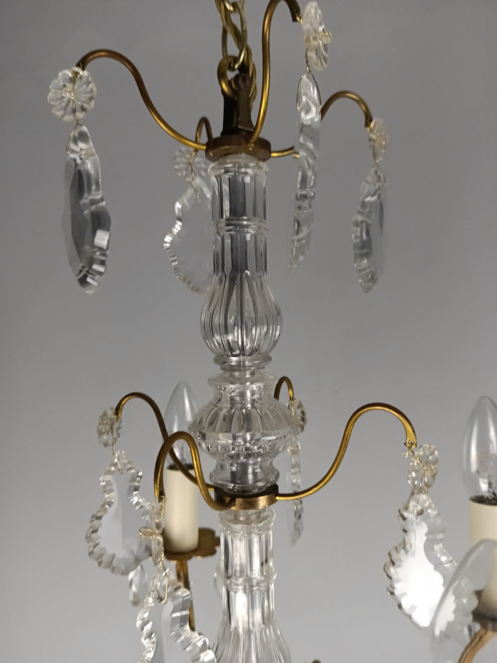 A four-light French gilded brass chandelier featuring a central glass column and hanging cut crystal drops. View IV