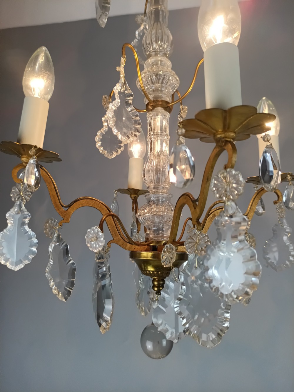 A four-light French gilded brass chandelier featuring a central glass column and hanging cut crystal drops. View XIII