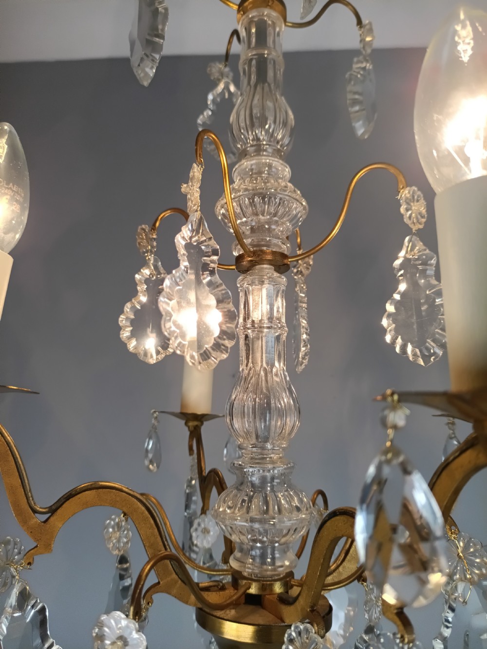 A four-light French gilded brass chandelier featuring a central glass column and hanging cut crystal drops. View XIV