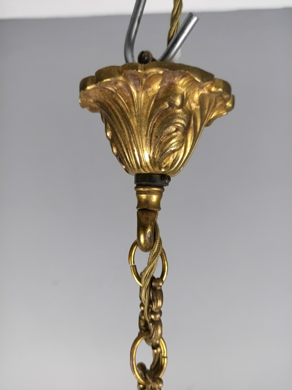 A six-arm French gilt brass chandelier featuring ornate acanthus scrollwork and white candle-style light sockets. View VIII