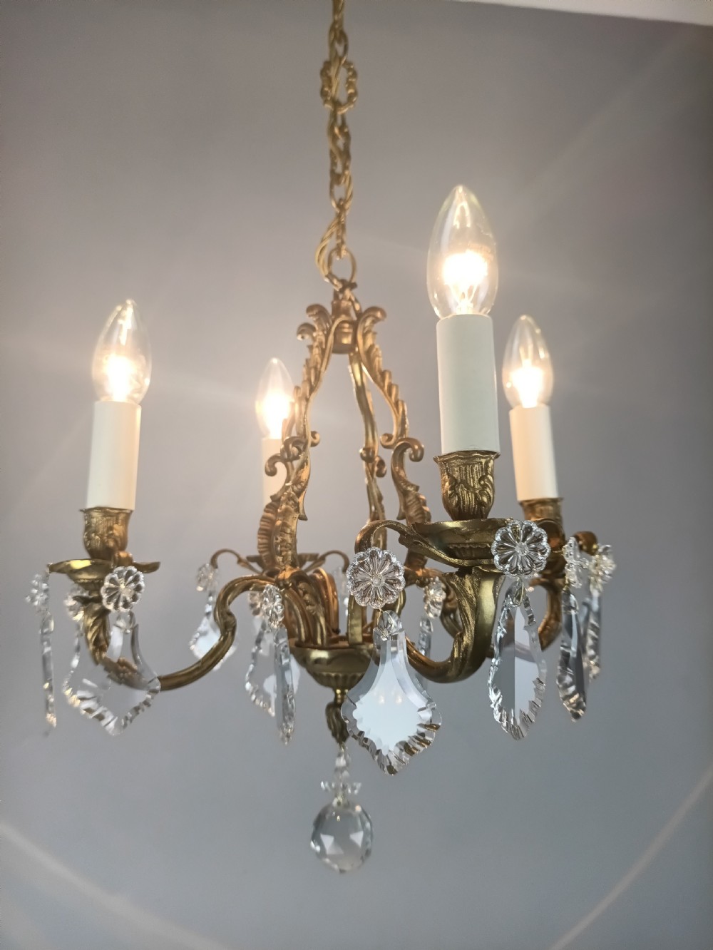 A four-arm French gilded brass chandelier adorned with cut crystal drops and cream candle-effect light holders. View III