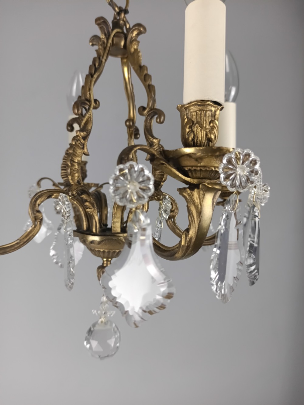 A four-arm French gilded brass chandelier adorned with cut crystal drops and cream candle-effect light holders. View VII