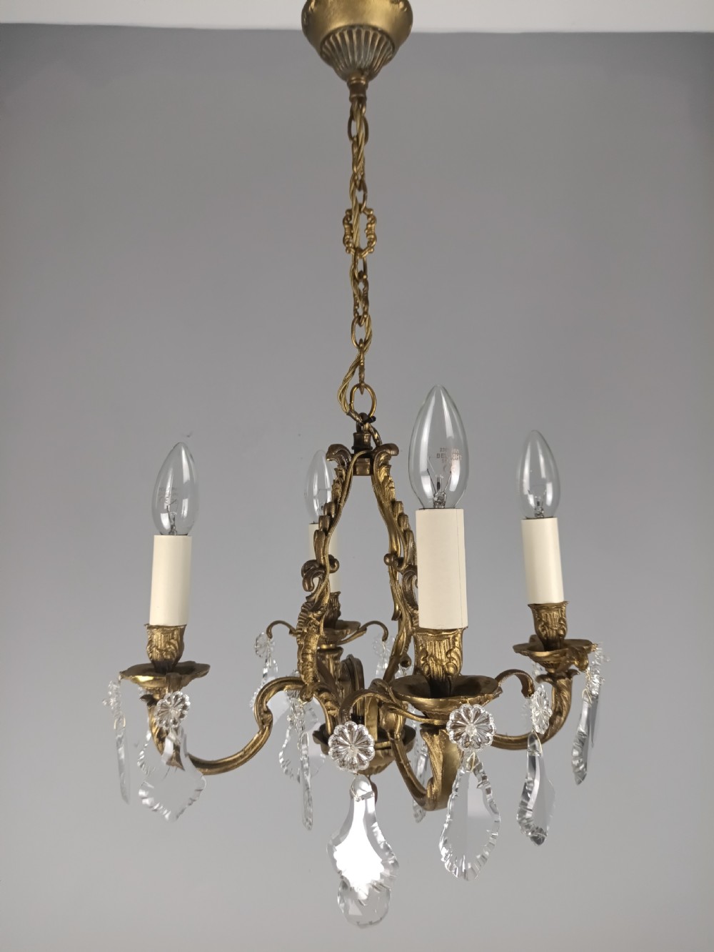 A four-arm French gilded brass chandelier adorned with cut crystal drops and cream candle-effect light holders. View IX