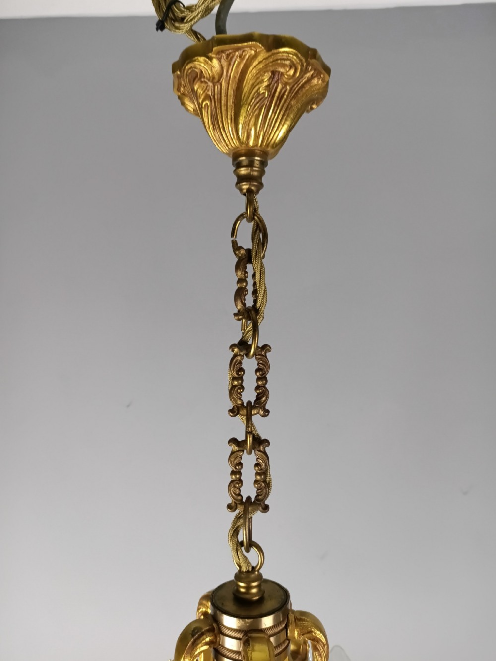 A French gilded brass five-arm chandelier featuring scrolling leaf motifs and faceted hanging crystal drops. View II