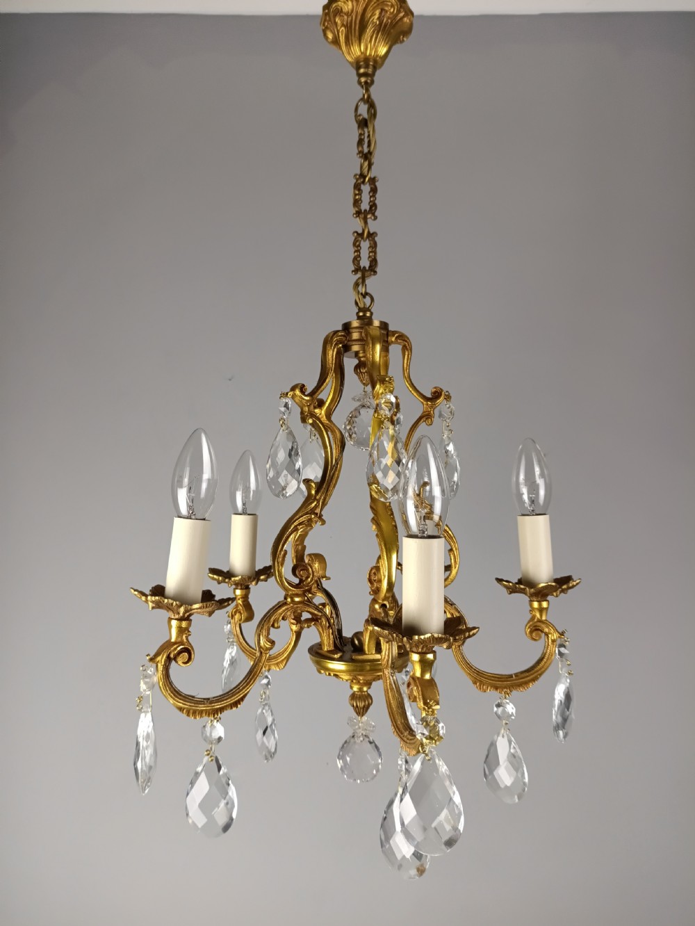 A French gilded brass five-arm chandelier featuring scrolling leaf motifs and faceted hanging crystal drops. View XII