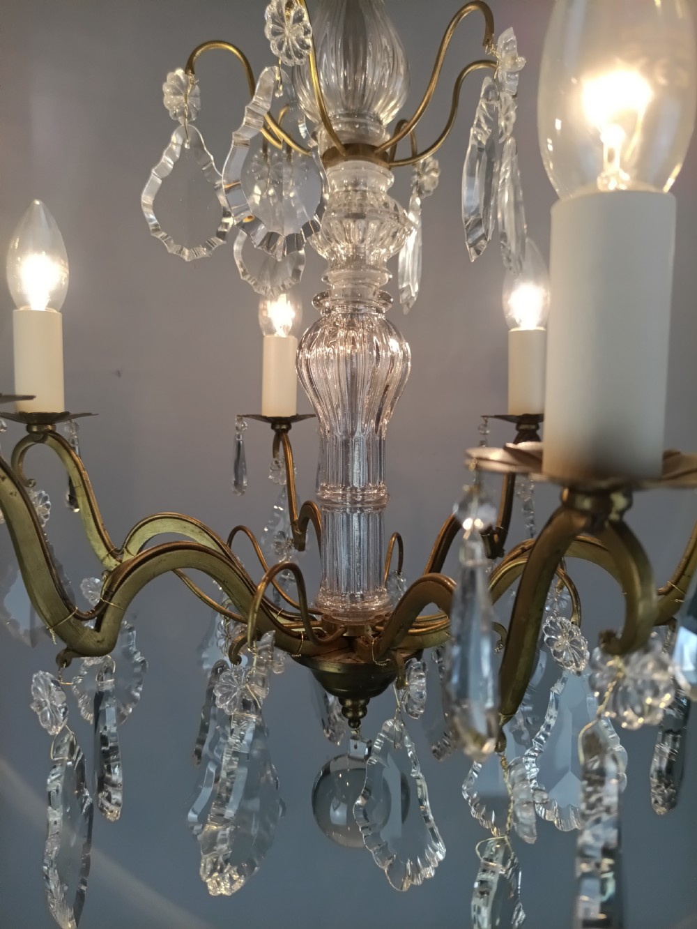 A French style gilt brass six arm chandelier embellished with clear glass stem sections and suspended crystal teardrop prisms. View VI