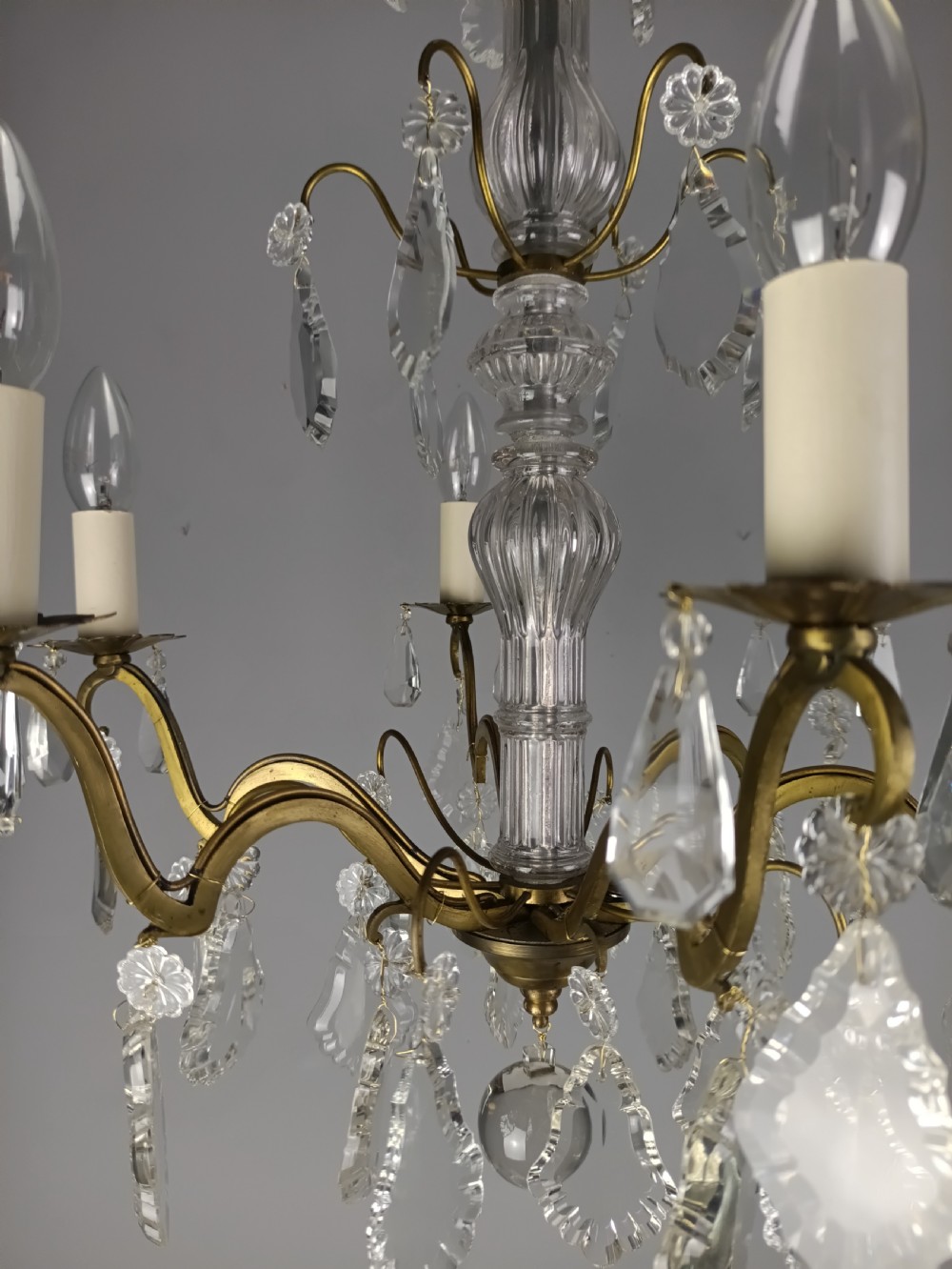 A French style gilt brass six arm chandelier embellished with clear glass stem sections and suspended crystal teardrop prisms. View IX