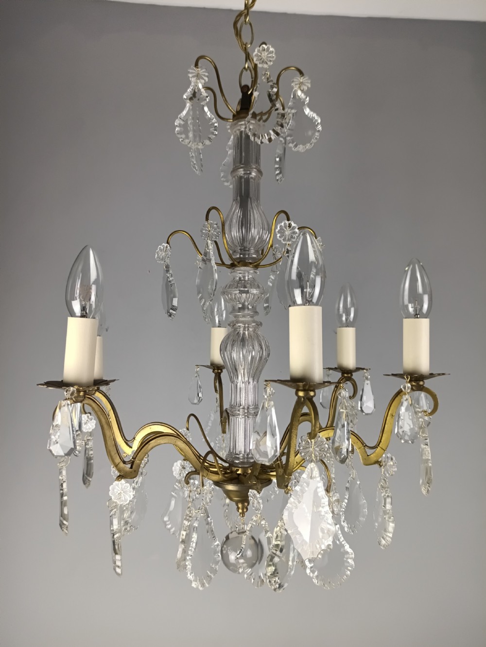A French style gilt brass six arm chandelier embellished with clear glass stem sections and suspended crystal teardrop prisms. View XI