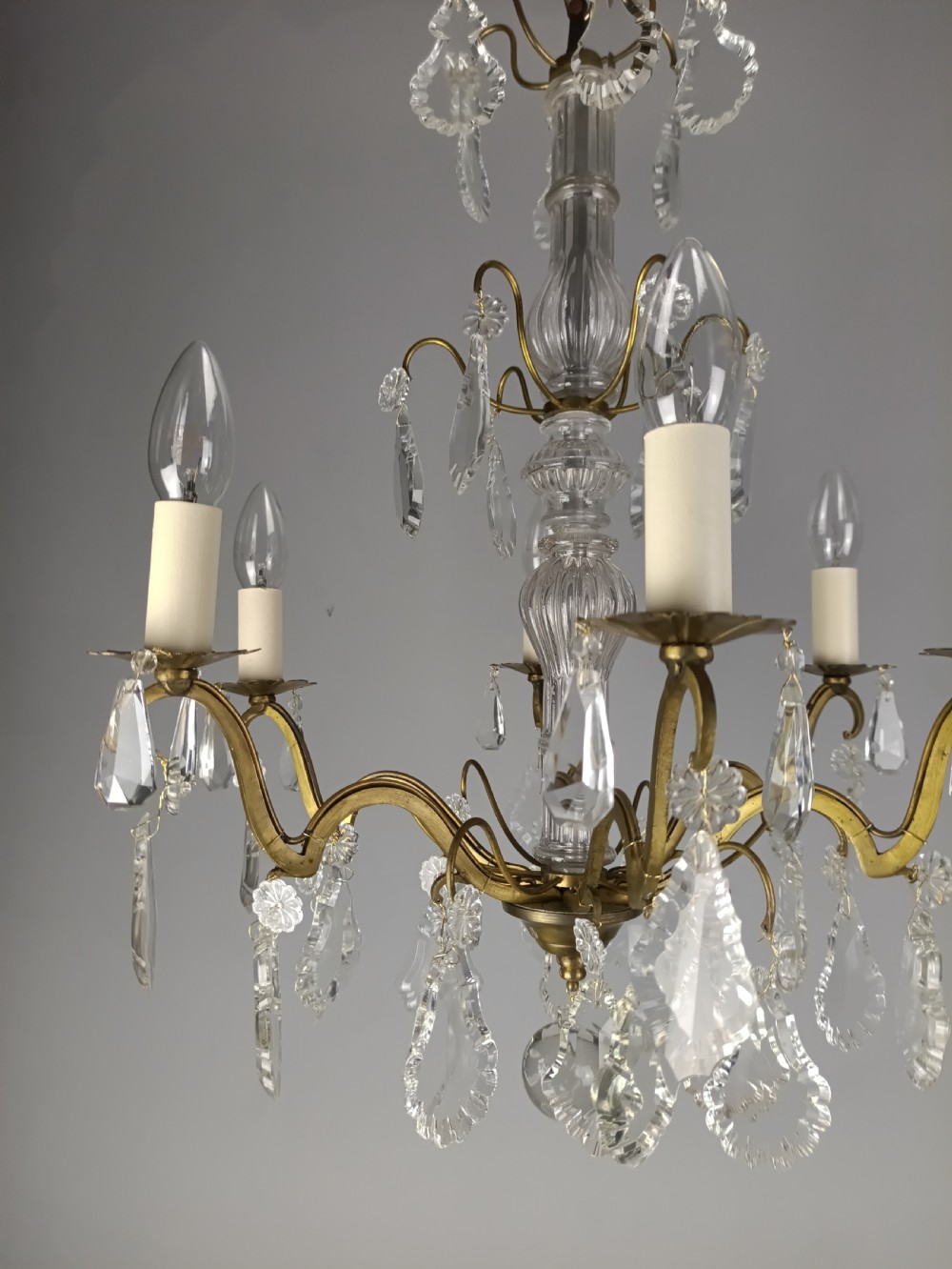 A French style gilt brass six arm chandelier embellished with clear glass stem sections and suspended crystal teardrop prisms. View XII