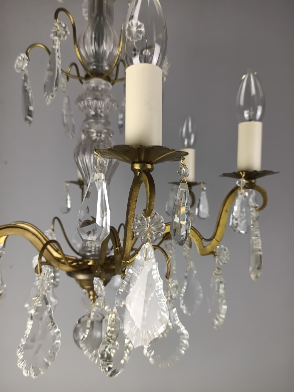 A French style gilt brass six arm chandelier embellished with clear glass stem sections and suspended crystal teardrop prisms. View XIII