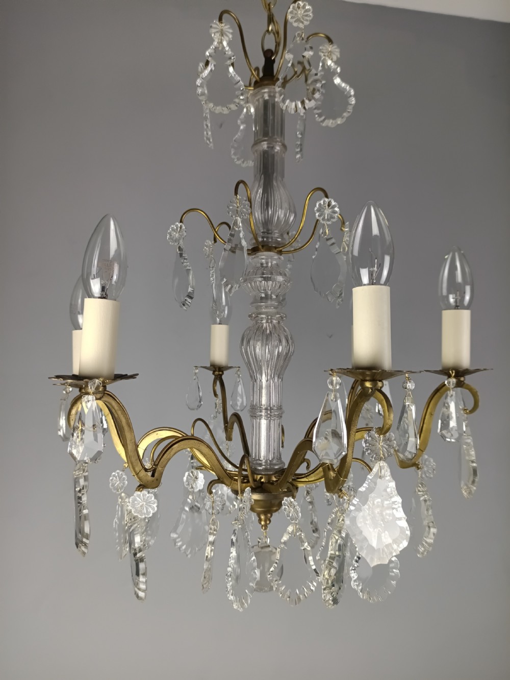 A French style gilt brass six arm chandelier embellished with clear glass stem sections and suspended crystal teardrop prisms. View XV