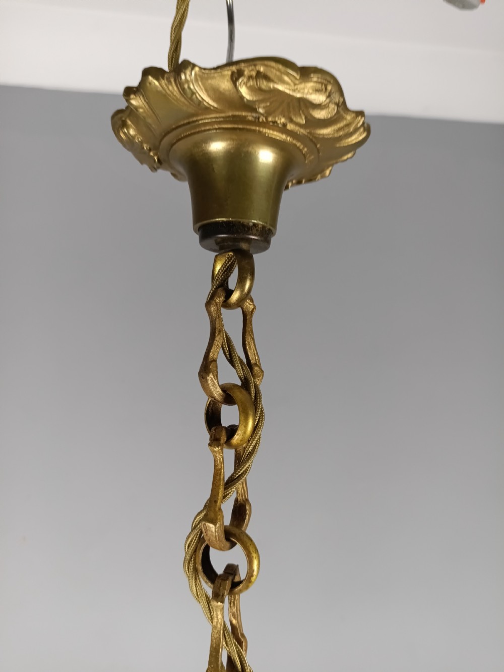 A French gilt brass six-arm chandelier featuring scrolled acanthus leaf branches, cream candle sleeves, and an ornate central column. View VII