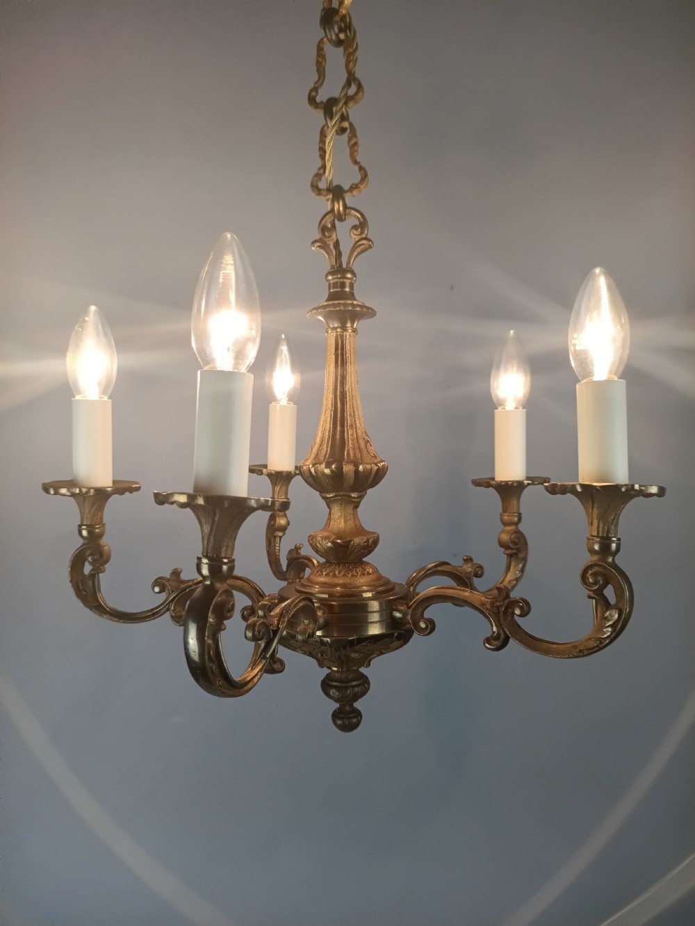 A French gilt brass five-arm chandelier featuring scrolling branch arms, candle bulb sleeves, and an ornate central column. View IV