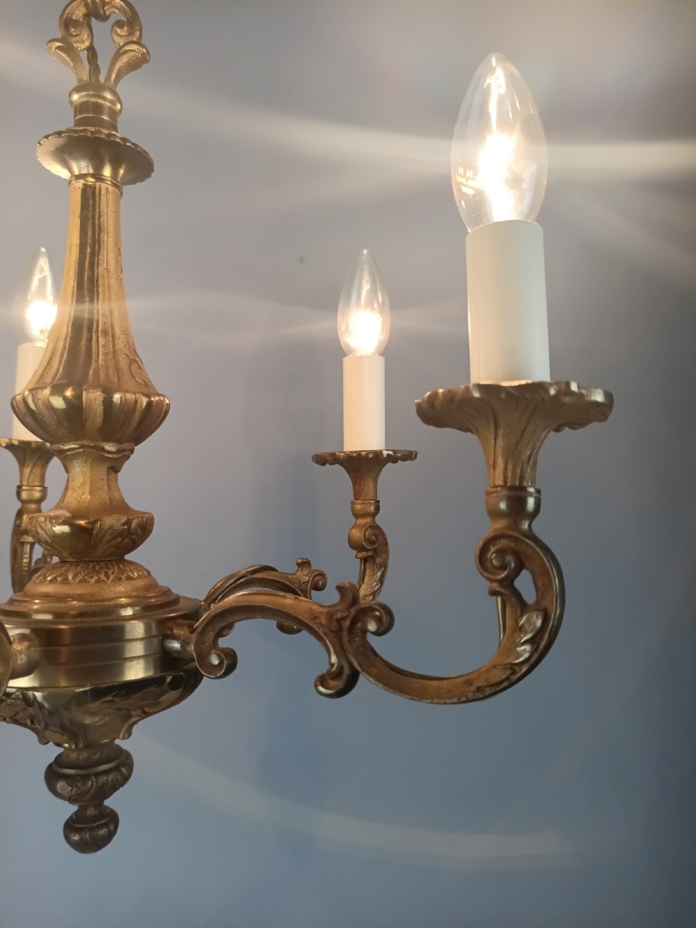 A French gilt brass five-arm chandelier featuring scrolling branch arms, candle bulb sleeves, and an ornate central column. View V