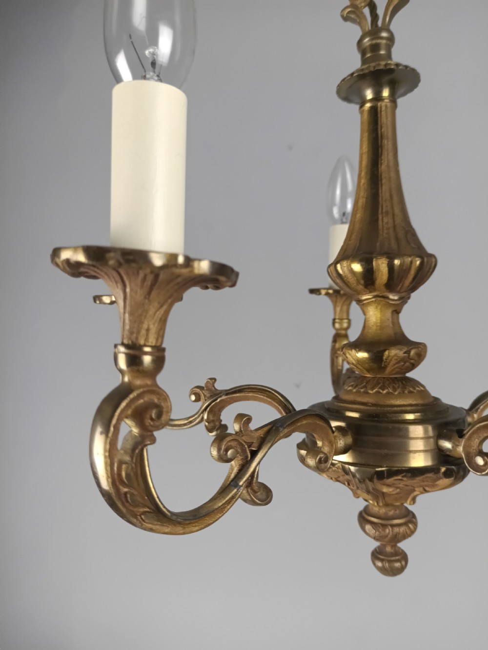 A French gilt brass five-arm chandelier featuring scrolling branch arms, candle bulb sleeves, and an ornate central column. View XIII