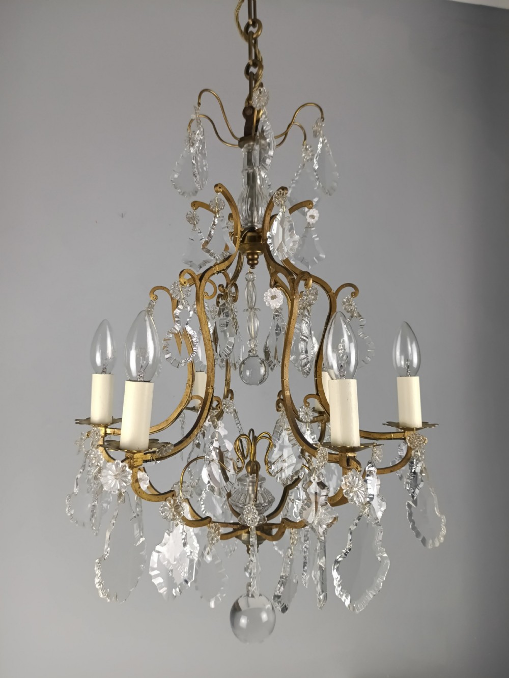 An antique French six-light birdcage chandelier featuring a gilded frame hung with clear crystal drops and glass rosettes. View IV