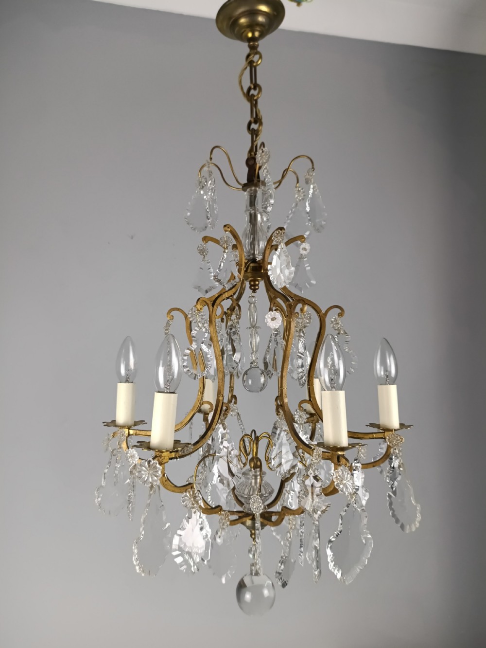 An antique French six-light birdcage chandelier featuring a gilded frame hung with clear crystal drops and glass rosettes. View V