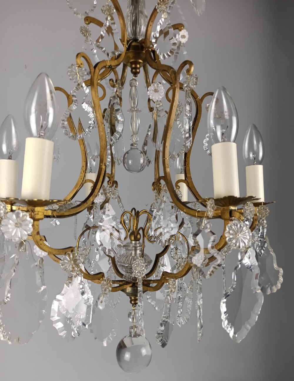 An antique French six-light birdcage chandelier featuring a gilded frame hung with clear crystal drops and glass rosettes. View VI