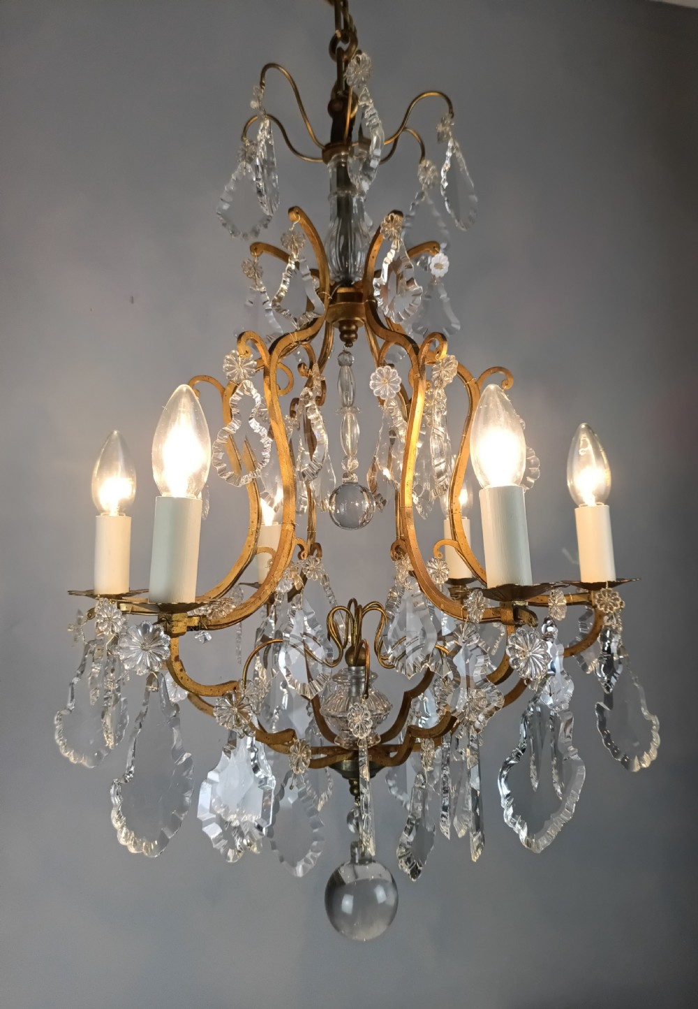 An antique French six-light birdcage chandelier featuring a gilded frame hung with clear crystal drops and glass rosettes. View VII