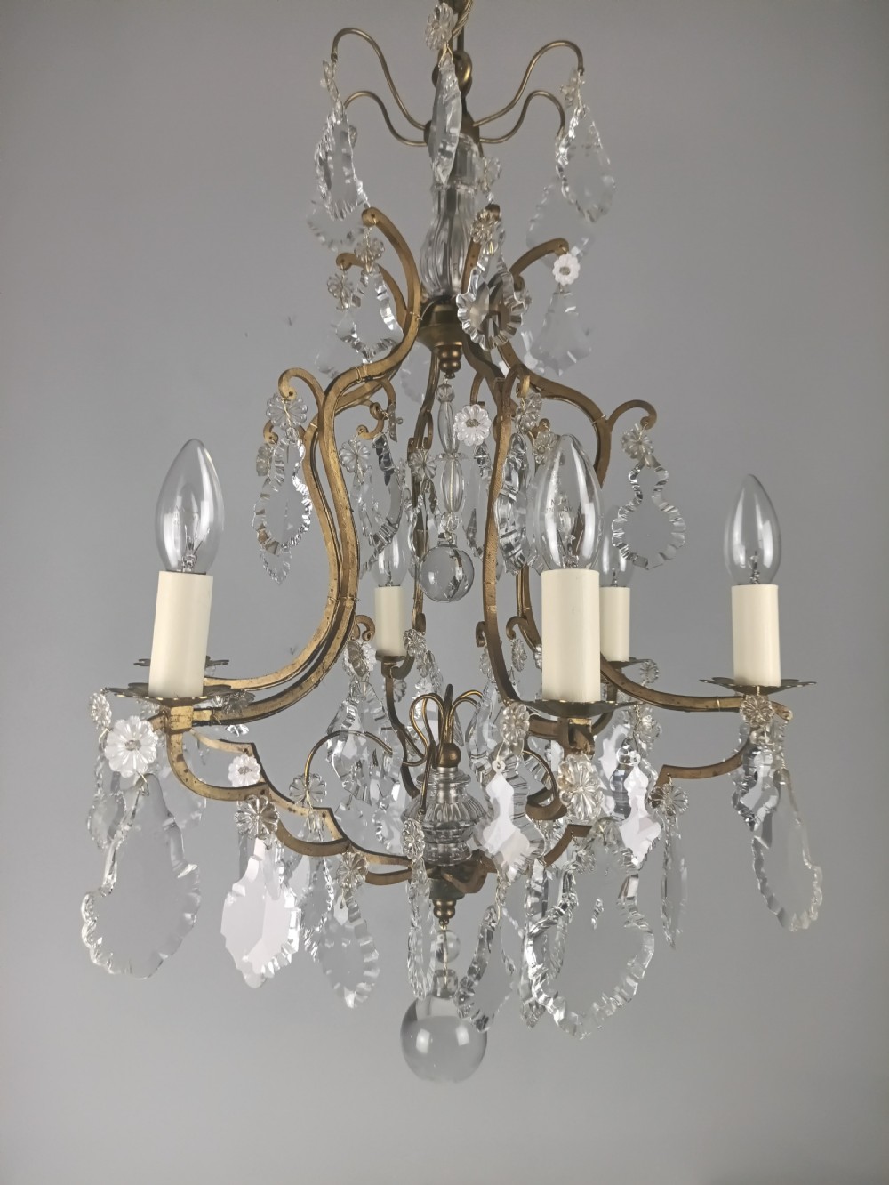 An antique French six-light birdcage chandelier featuring a gilded frame hung with clear crystal drops and glass rosettes. View X