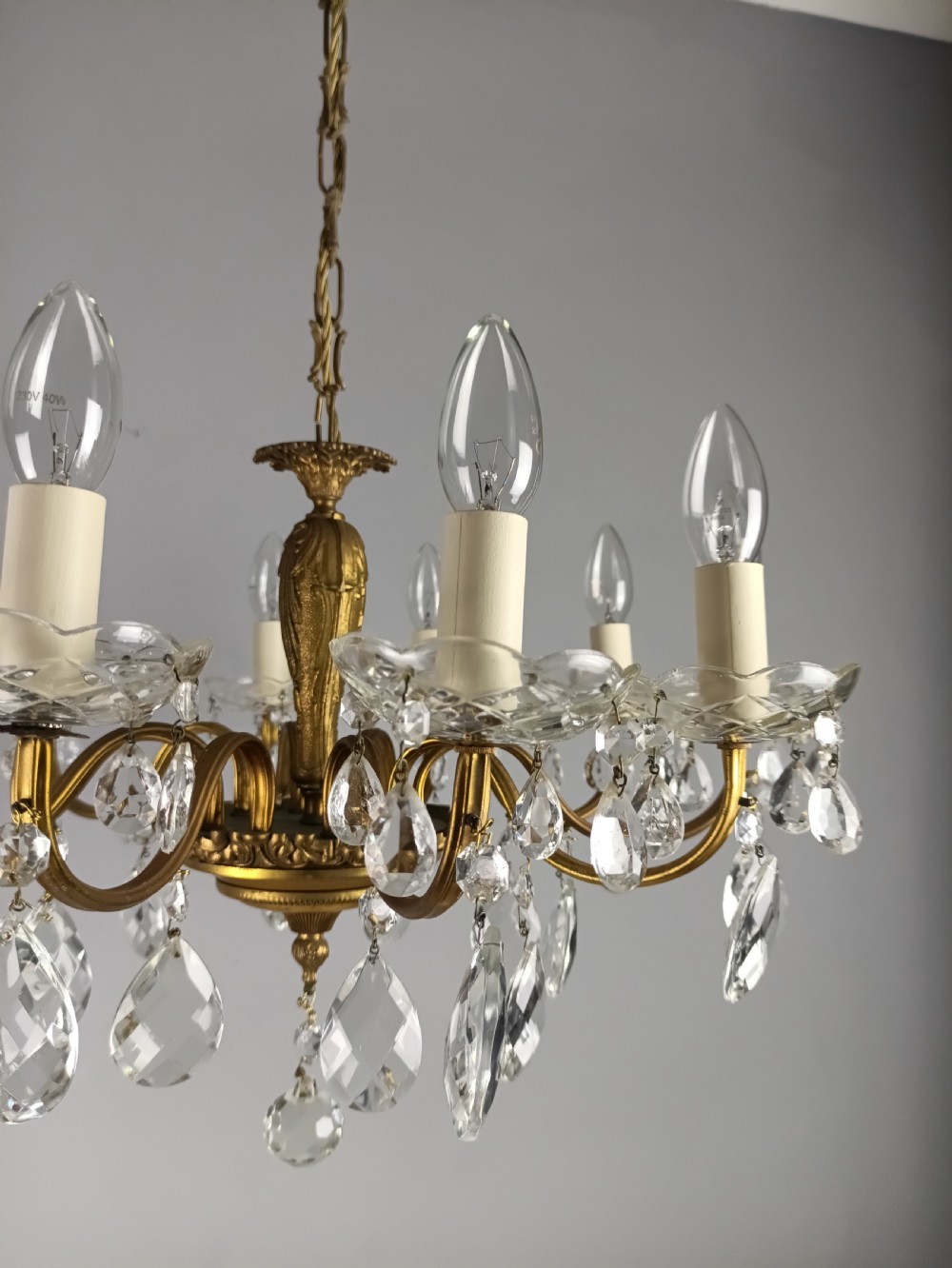 A French style gilt brass ten-light chandelier featuring curved candle arms, glass bobeches, and faceted hanging glass drops. View V