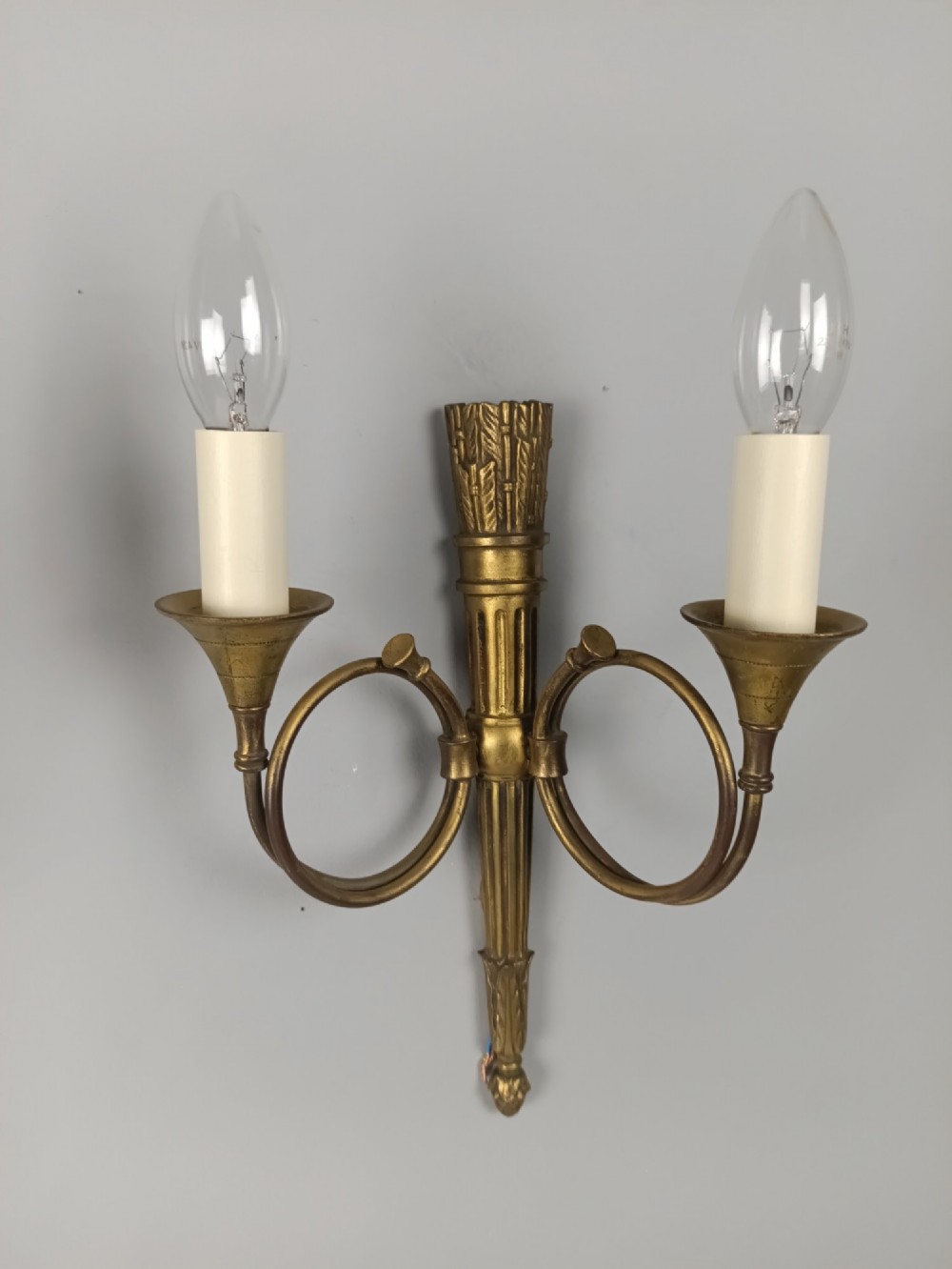 A set of four French Empire style gilt brass wall lights, each featuring two curved hunting horn arms extending from a central torch-form backplate. View II