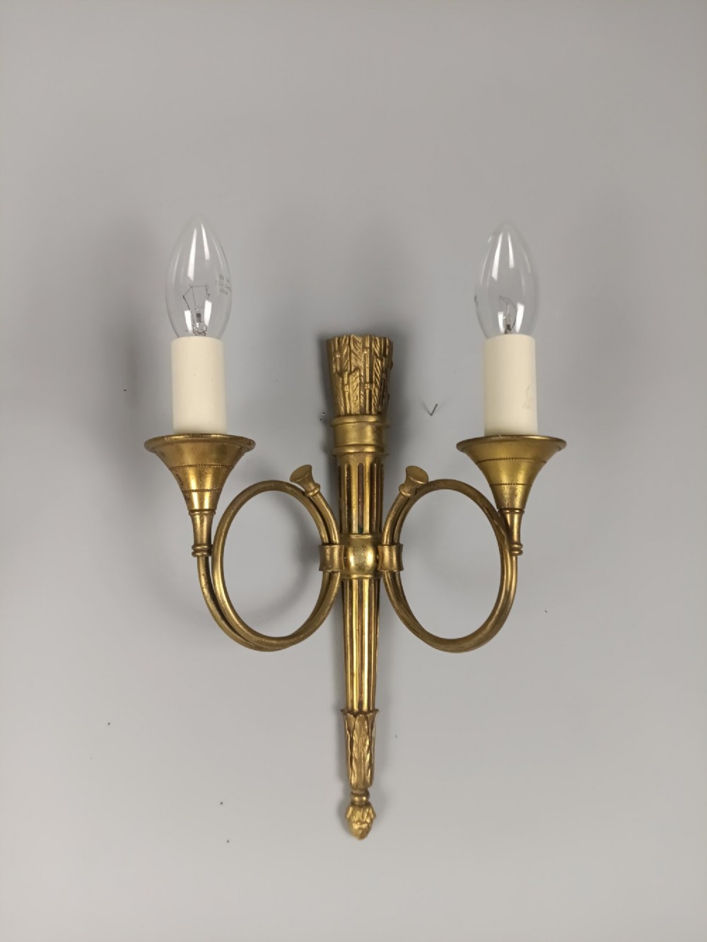 A set of four French Empire style gilt brass wall lights, each featuring two curved hunting horn arms extending from a central torch-form backplate. View III