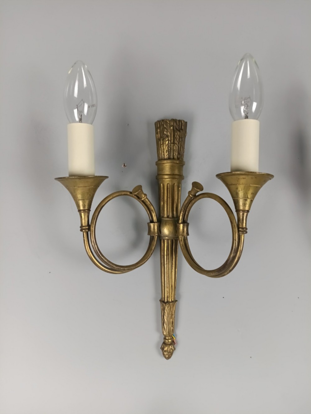 A set of four French Empire style gilt brass wall lights, each featuring two curved hunting horn arms extending from a central torch-form backplate. View IV