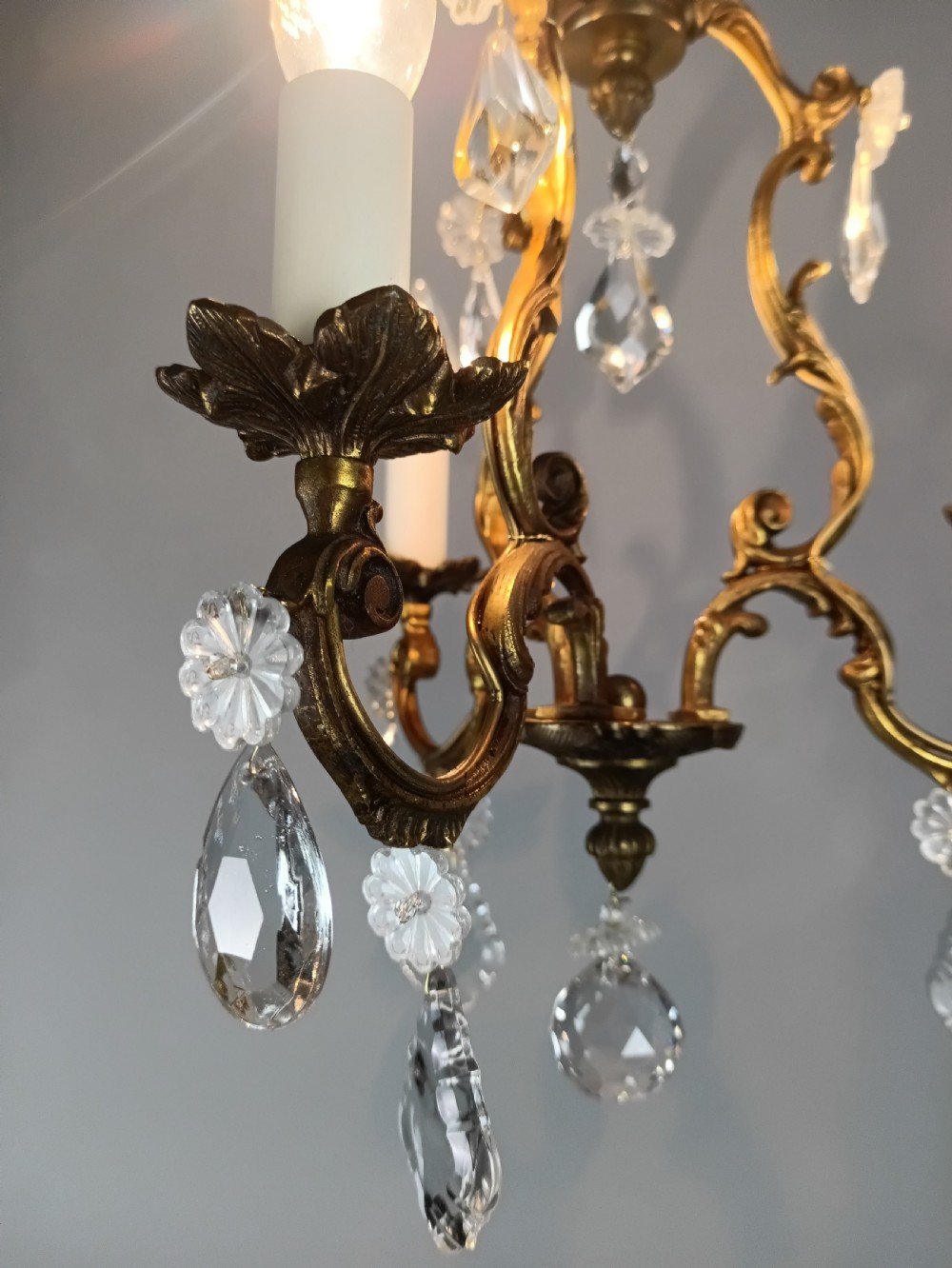 A French Rococo style three-light gilded brass chandelier decorated with suspended cut crystal drops and candle-effect light holders. View VIII