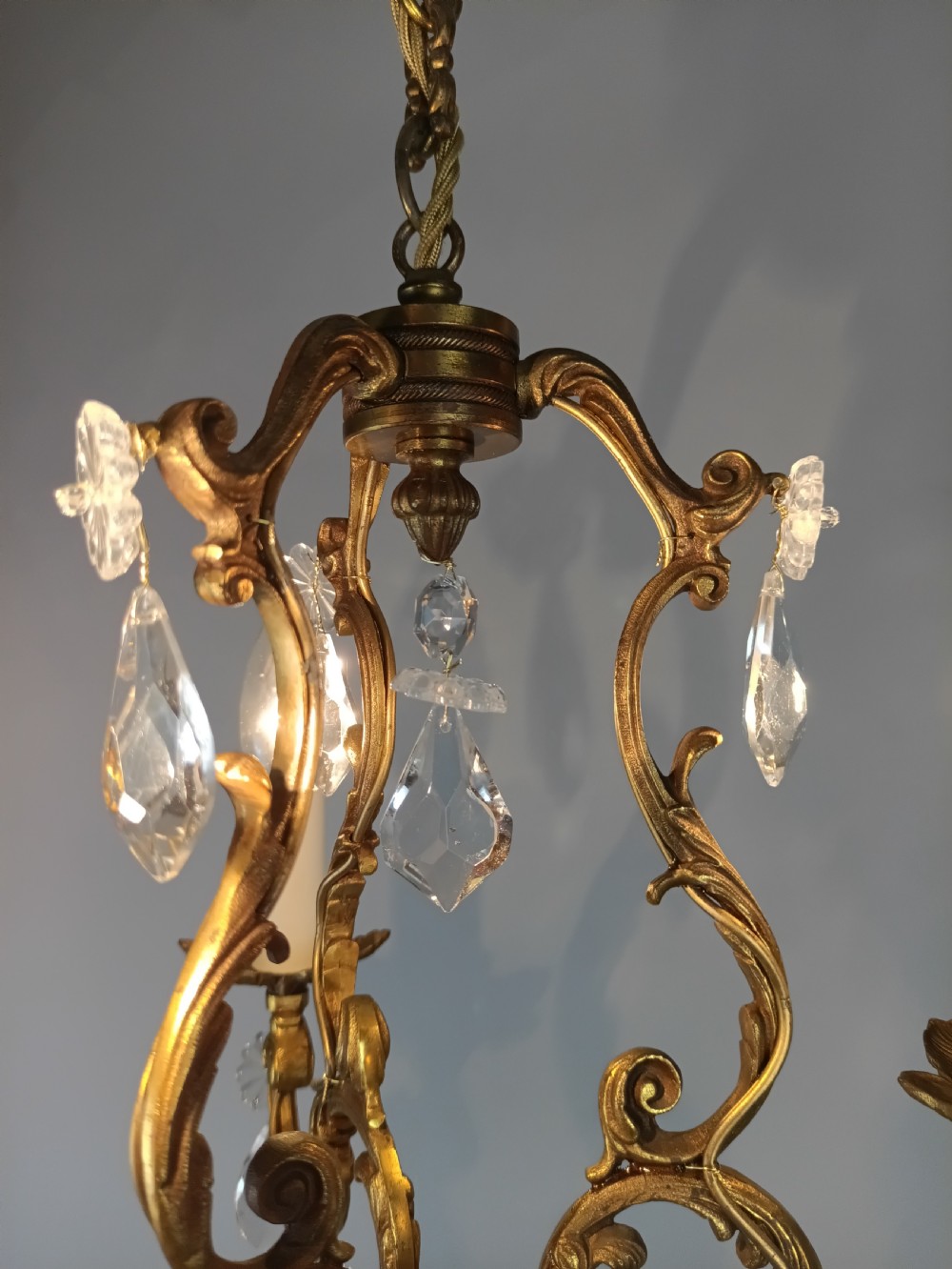 A French Rococo style three-light gilded brass chandelier decorated with suspended cut crystal drops and candle-effect light holders. View IX
