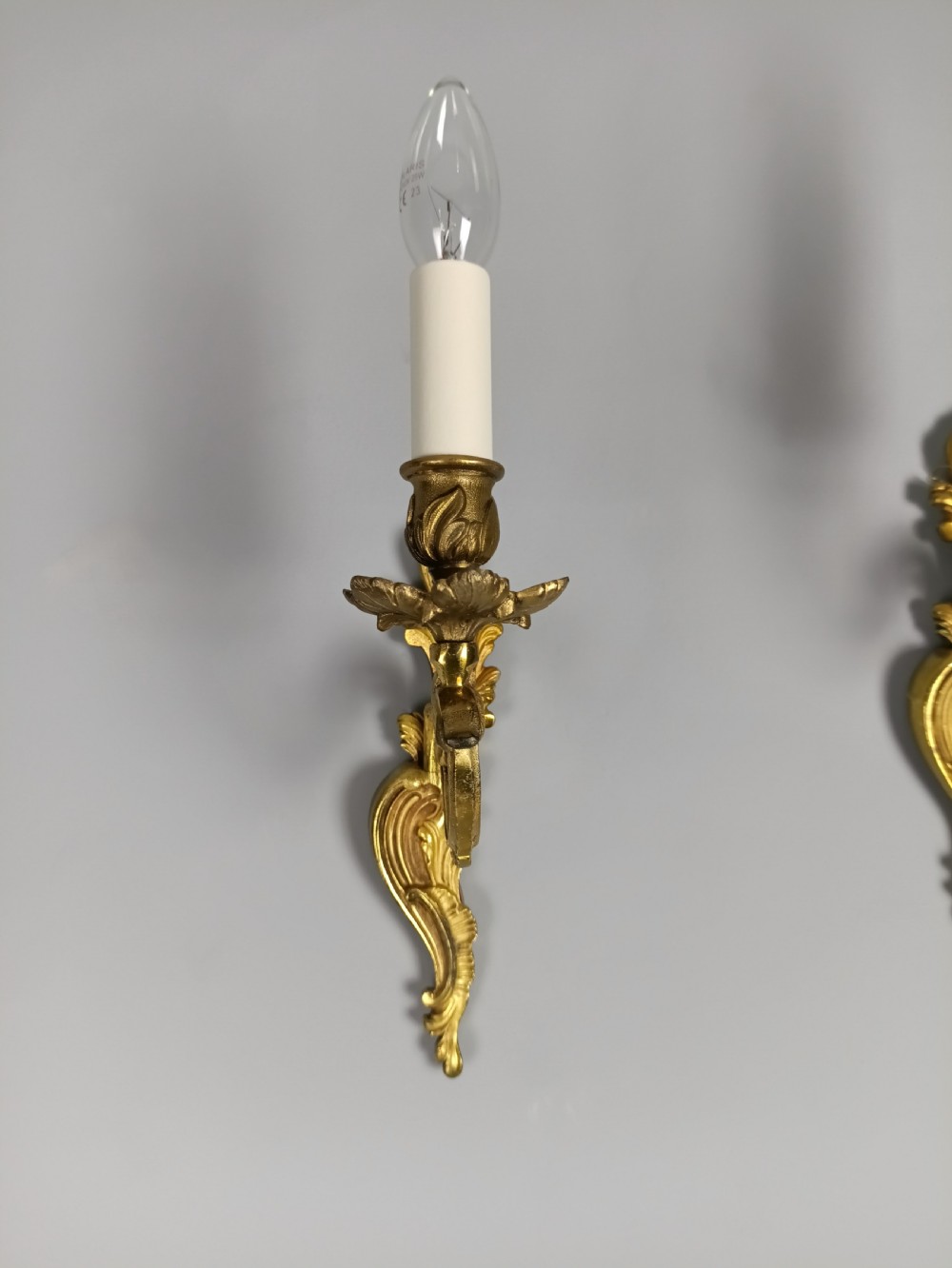 A pair of French gilt brass single-arm wall lights with acanthus leaf backplates and candle bulb fittings. View IV