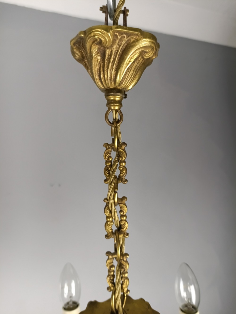 A matching pair of five-arm French gilt brass chandeliers featuring scrolling foliate arms, candle-effect sockets, and decorative hanging chains. View VII