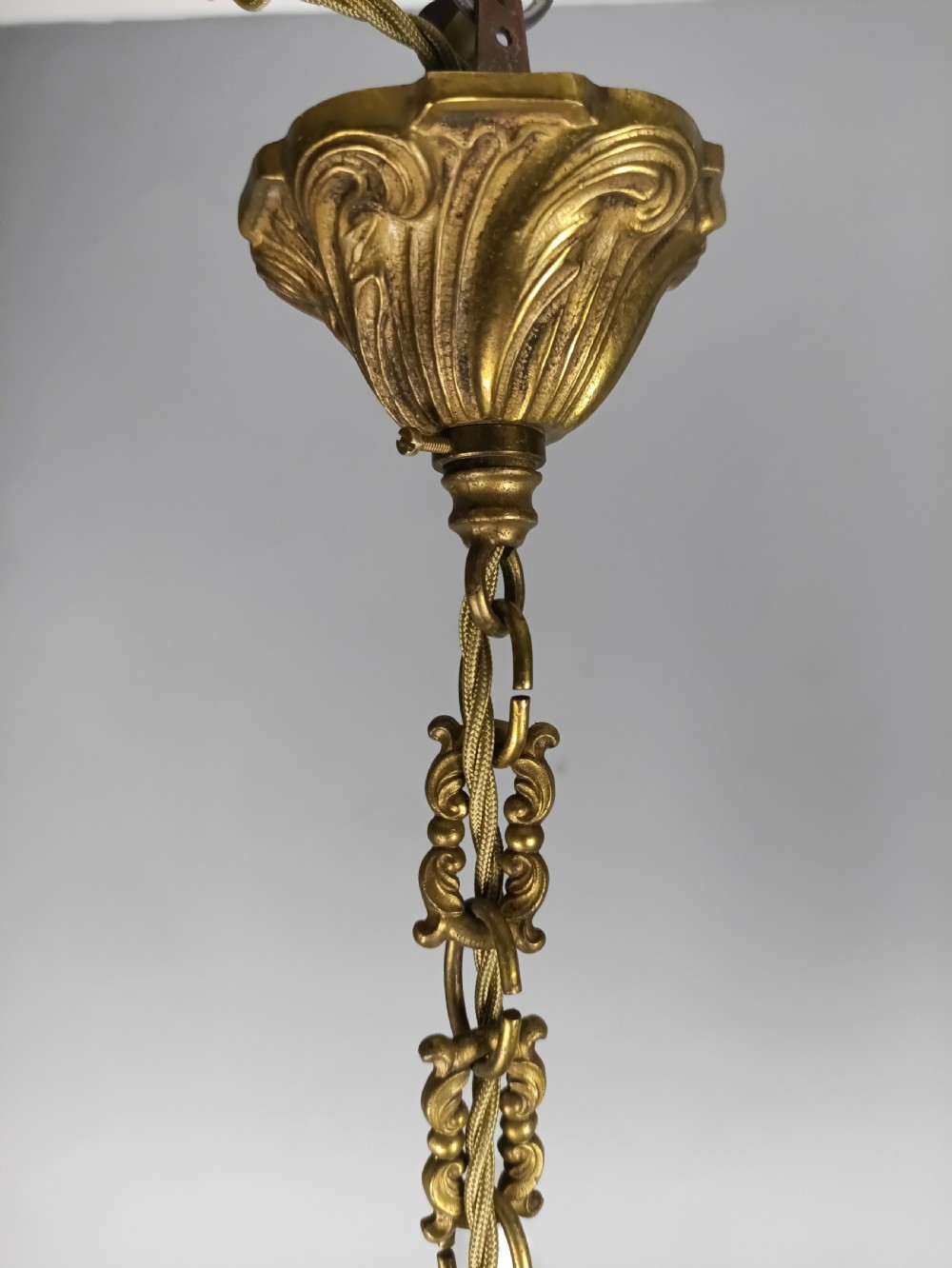 A matching pair of five-arm French gilt brass chandeliers featuring scrolling foliate arms, candle-effect sockets, and decorative hanging chains. View VIII