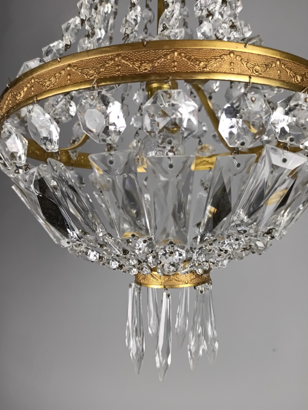 An antique French tent and bag chandelier featuring cascading crystal beads attached to a decorative brass rim with cut glass prisms below. View II