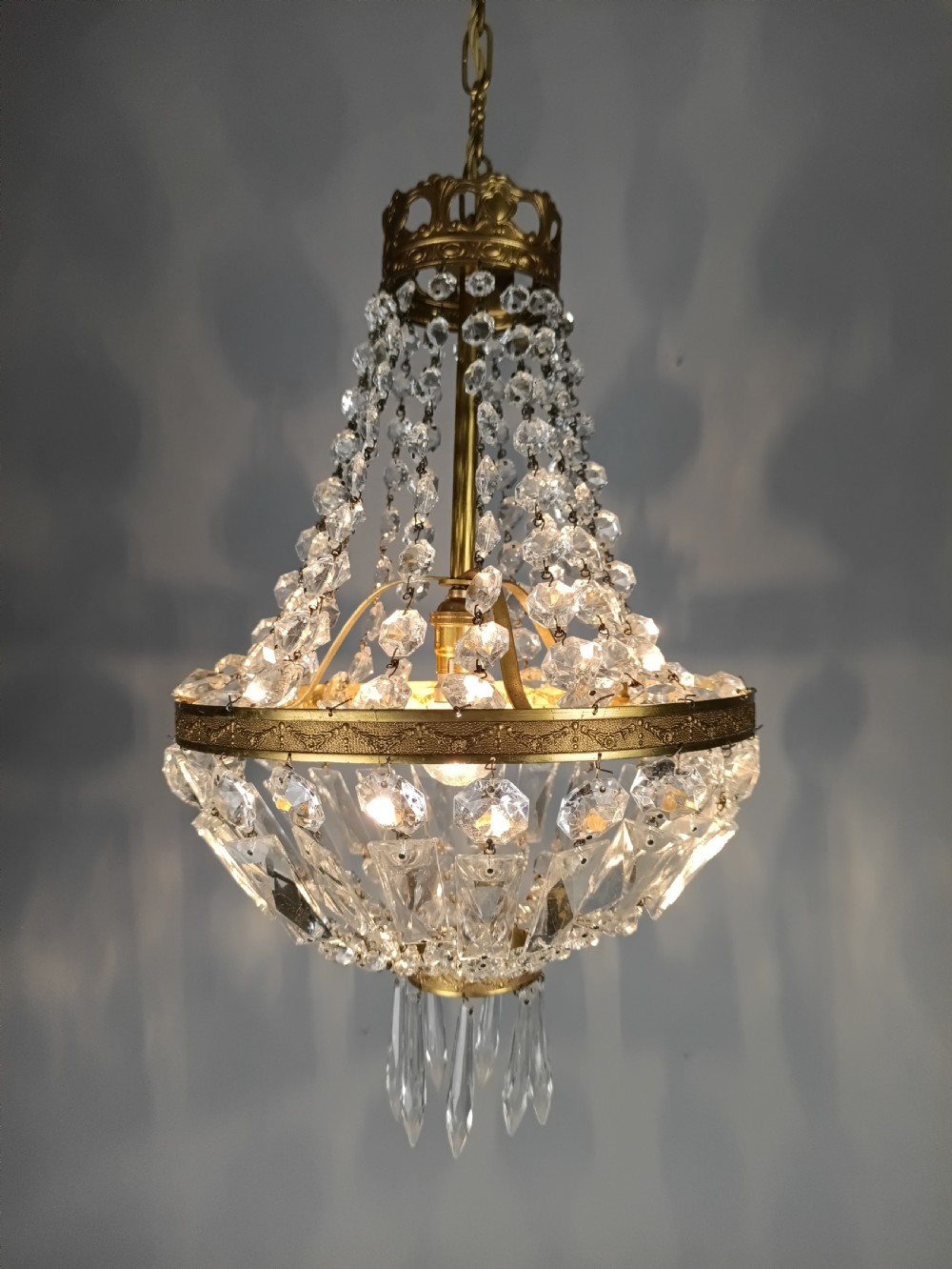 An antique French tent and bag chandelier featuring cascading crystal beads attached to a decorative brass rim with cut glass prisms below. View IV